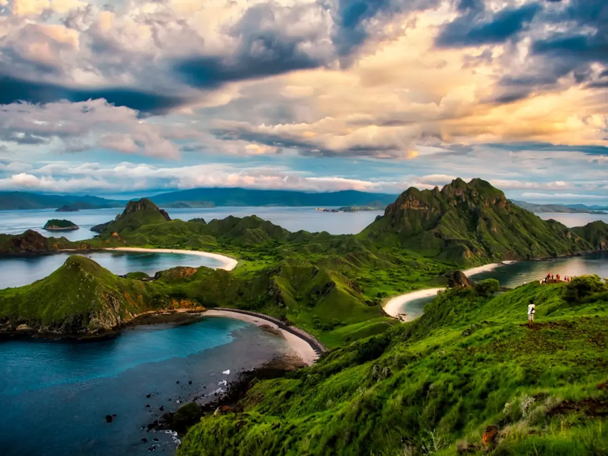 green and brown mountains near body of water under white clouds and blue sky during daytim